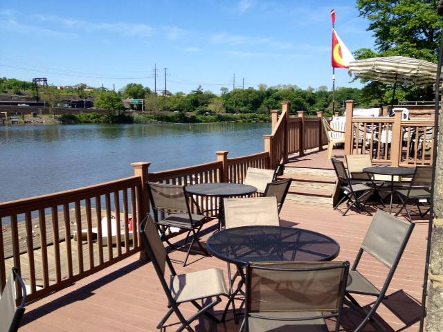 The riverfront deck at Crescent Boat Club set with tables and chairs above the Schuylkill River